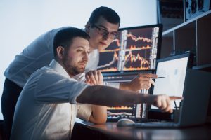 team stockbrokers are having conversation dark office with display screens analyzing data graphs reports investment purposes creative teamwork traders